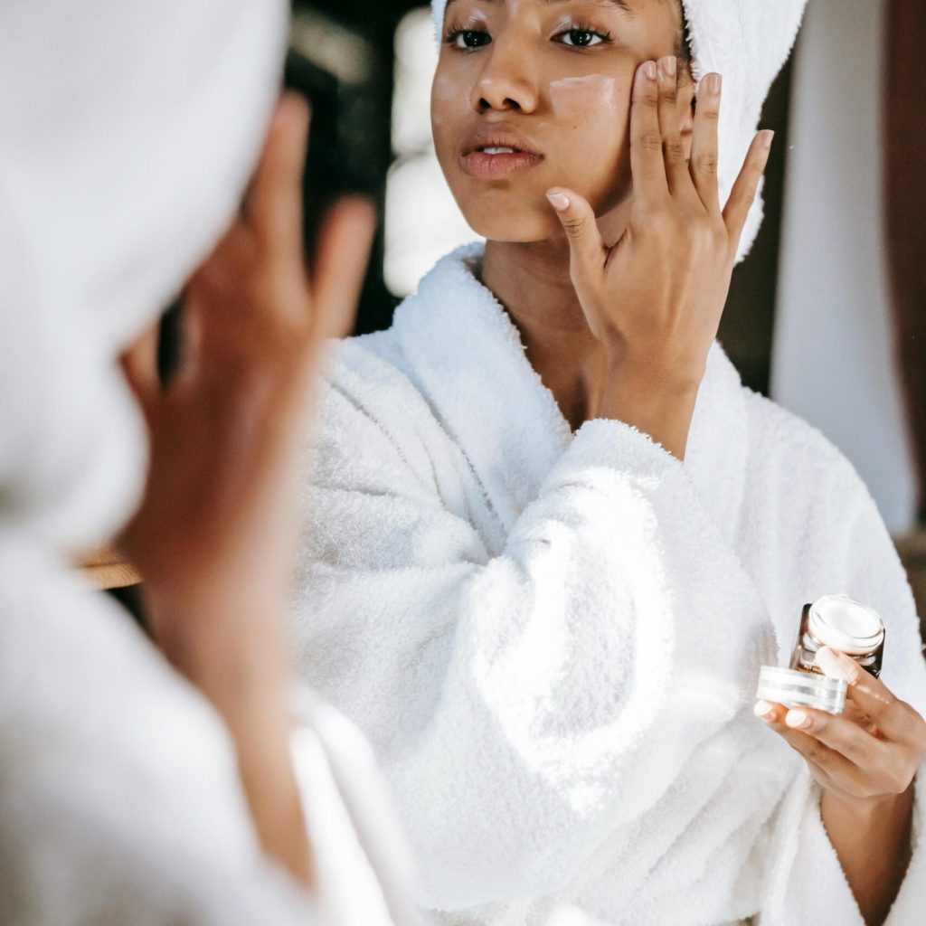 Persona che si sguarda allo specchio mentre fa la skincare